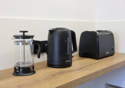 Schwarze Küchengeräte auf Holzregal in moderner Küche