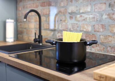 Kochtopf mit Spaghetti auf moderner Herdplatte in Küche