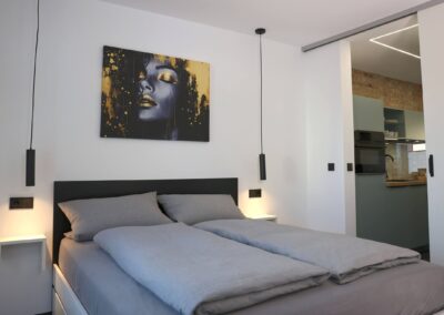 Modernes Schlafzimmer der Ferienwohnung Petra in Ilmenau mit Doppelbett, Pendelleuchten und Blick in die Küche