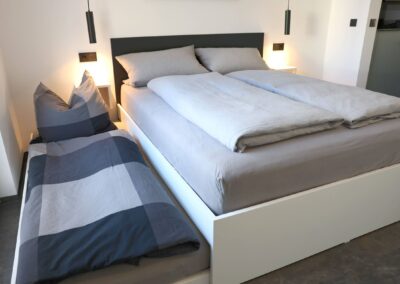 Geräumiges Schlafzimmer mit komfortablem Doppelbett, der Aufbettung für dritte Person, und Kleiderschrank in der Ferienwohnung Petra Ilmenau – erholsam übernachten im Thüringer Wald