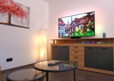 Gemütliches Wohnzimmer mit Flachbild-TV, Holz-Sideboard und rundem Couchtisch in der Ferienwohnung Petra in Ilmenau